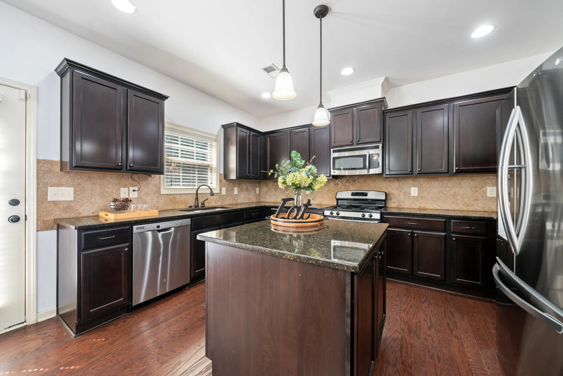 Kitchen with dark cabinetry, stone counters and center island